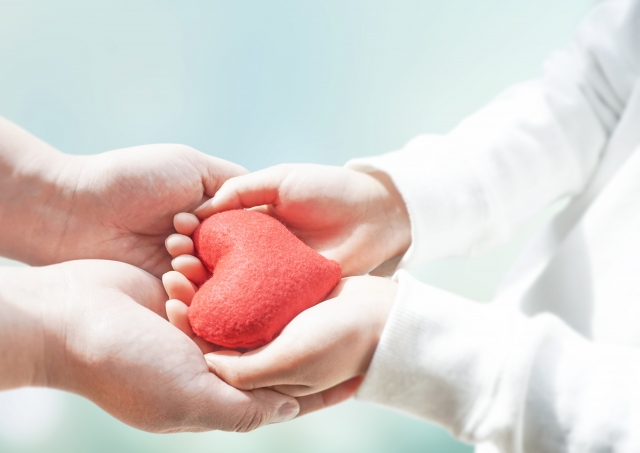 母親と子どもが手を取り合い、ハートを持っている