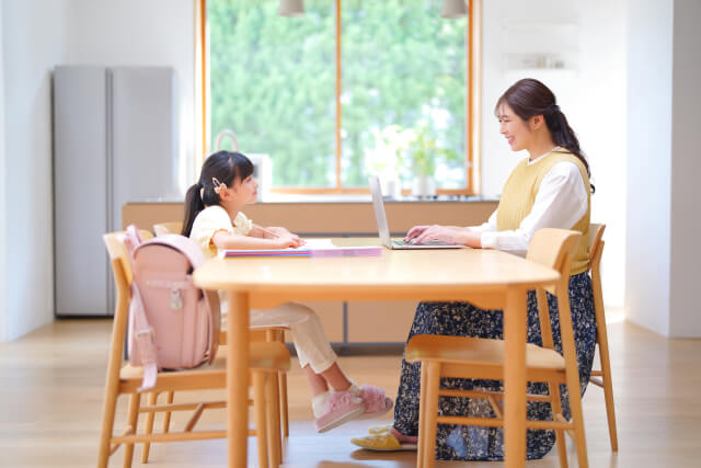 帰宅後の小学生と一緒に在宅ワークをする母親
