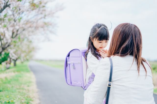 ランドセルを背負った小学生を見送る女性
