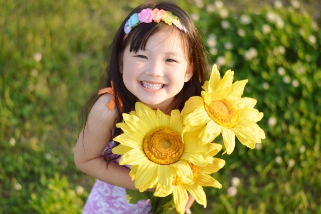 ひまわりの花を持ち笑う女の子